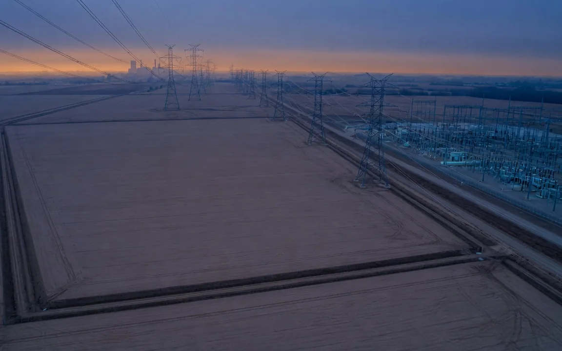 Aerial of a power-vetted Ontario industrial parcel at blue hour, with a substation and transmission line along its edge